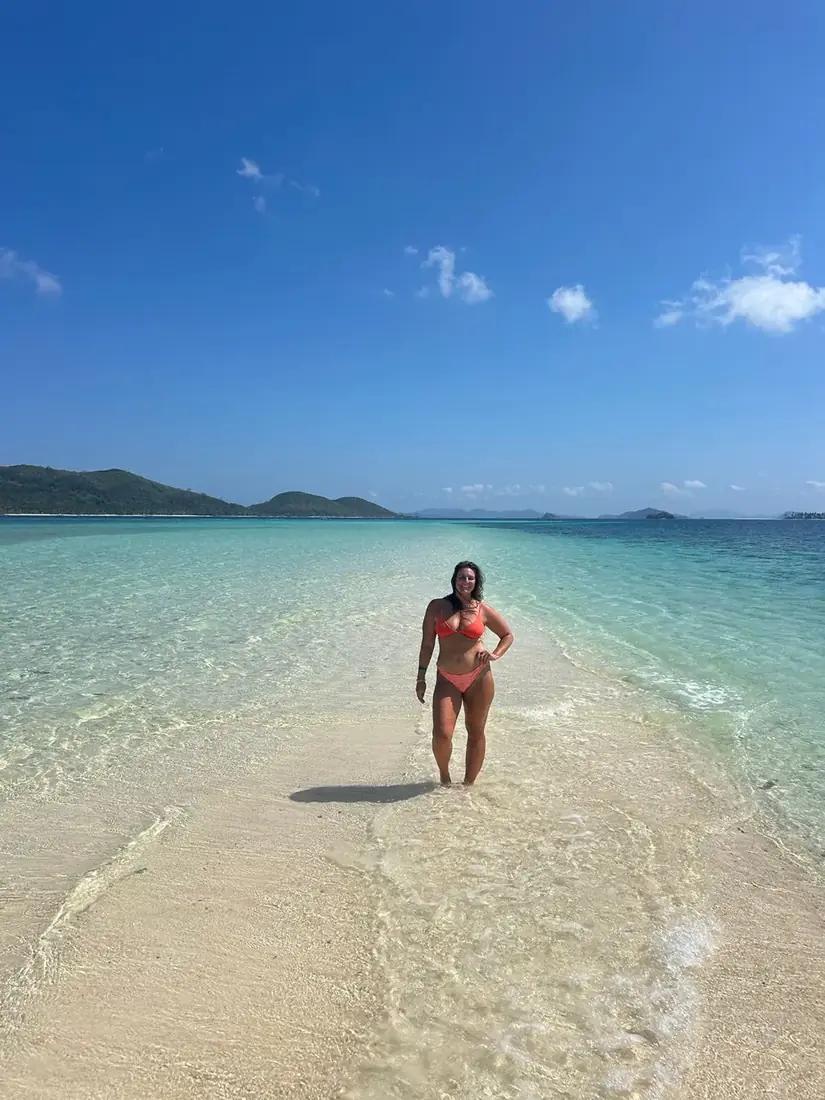 Alana walking along a white-sand path into turquoise water