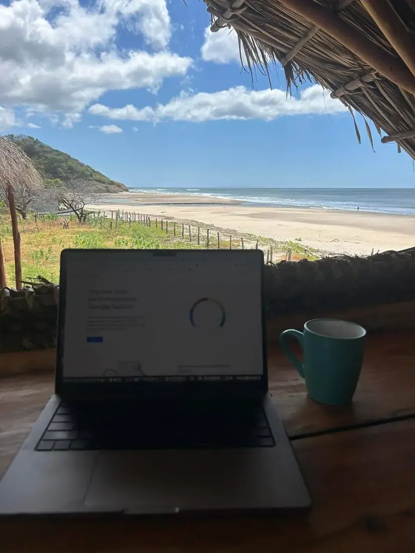 Laptop and mug overlooking a sweeping beach