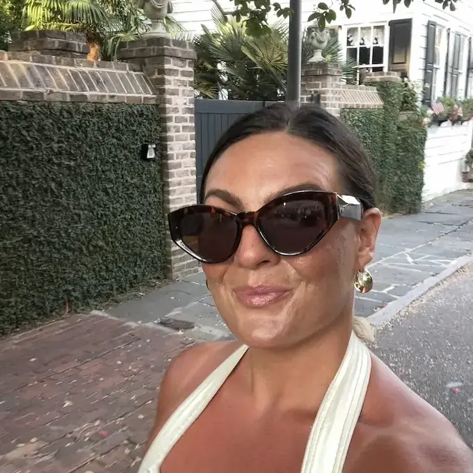 Alana in sunglasses on a palm-lined street