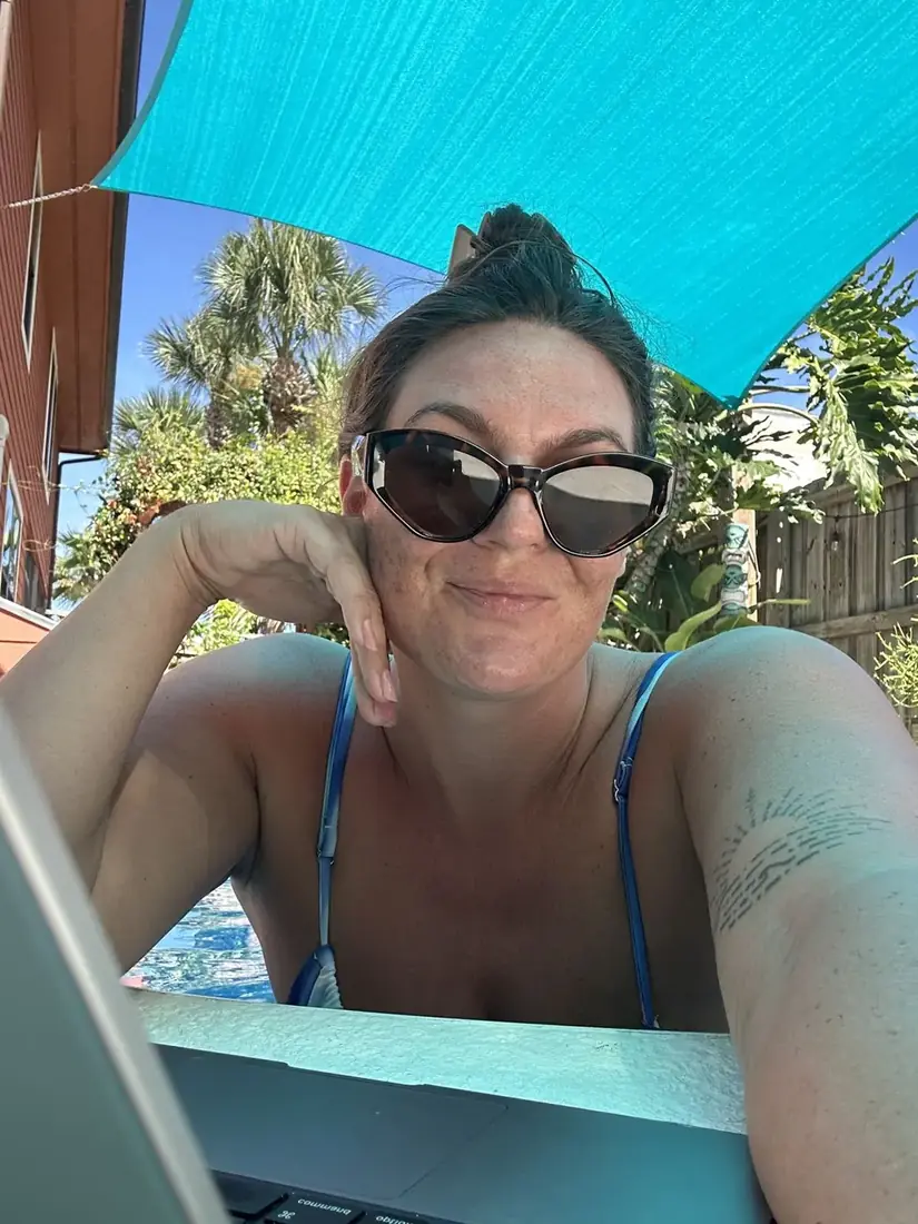 Alana working by the pool under a shade sail